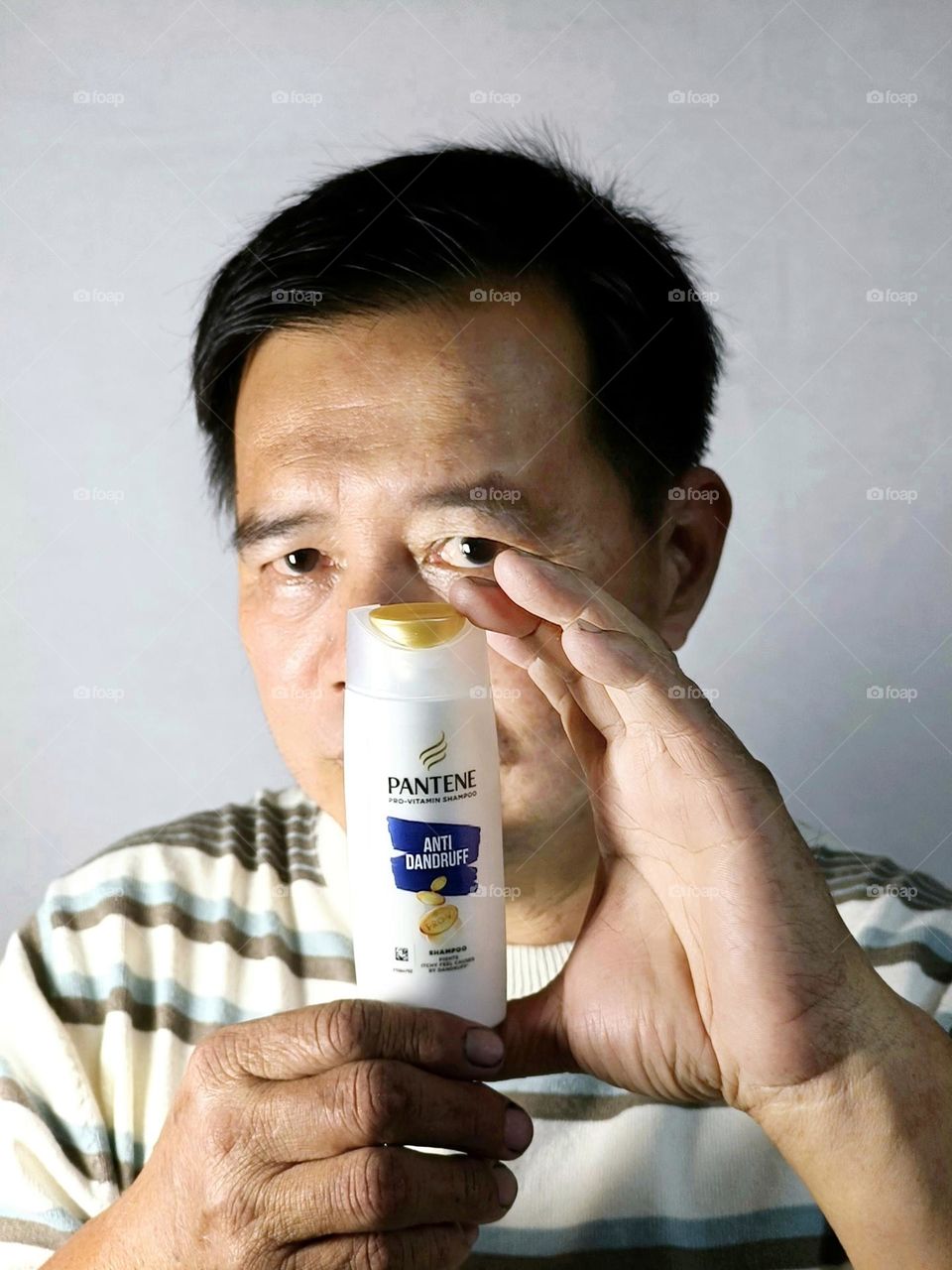 A Chinese man was holding a bottle of shampoo.