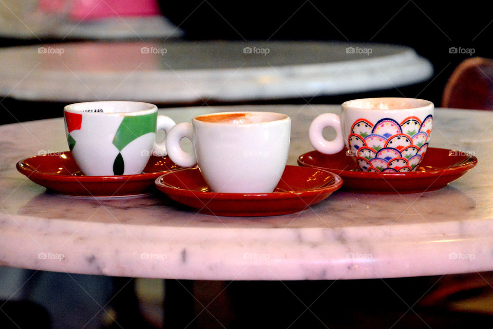 Three cups on saucers are seen on a table in a coffee shop. close up