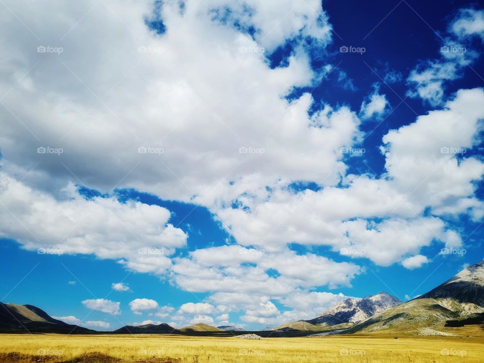 scattered clouds rise from the valley and shade the mountains