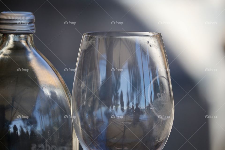 Clear clean crystal wine goblet beside plastic bottle of water: concept wine tasting sampling, refreshment, hydration, winery, party or celebration, outdoors natural light