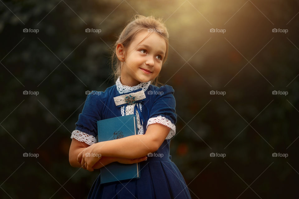 Little schoolgirl with a book at a park 