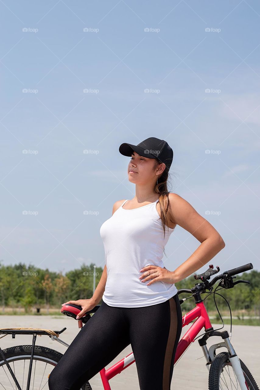 woman in sports clothes and cap riding her bicycle