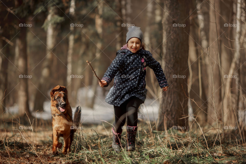 Girl walking with German shepherd puppy in a spring forest 