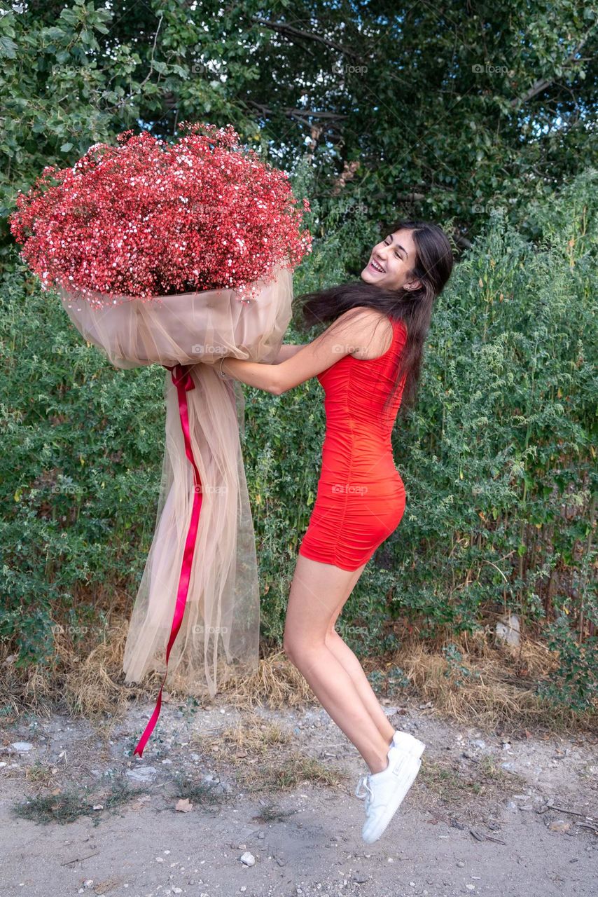 Beautiful Girl Dances with a Large Bouquet of Red Flowers