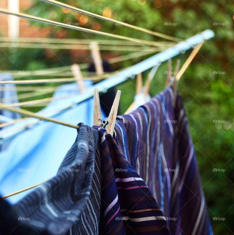 Laundry hanging on rotary dryer in garden using wooden clothes pegs  
