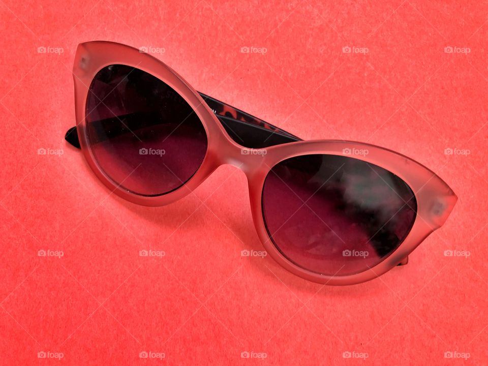 Orange sunglasses on red background