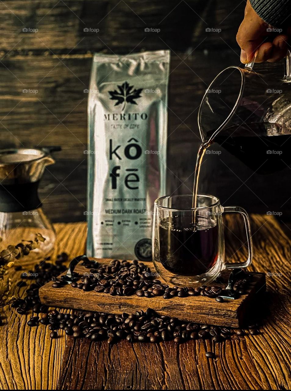 A cup of black hot coffee with a bag of coffee. Some coffee beans on top of the wooden board and table 