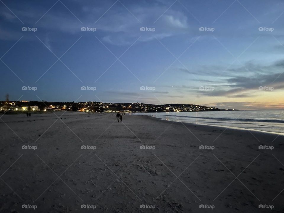 A night on a beach in Australia with lights in the background 