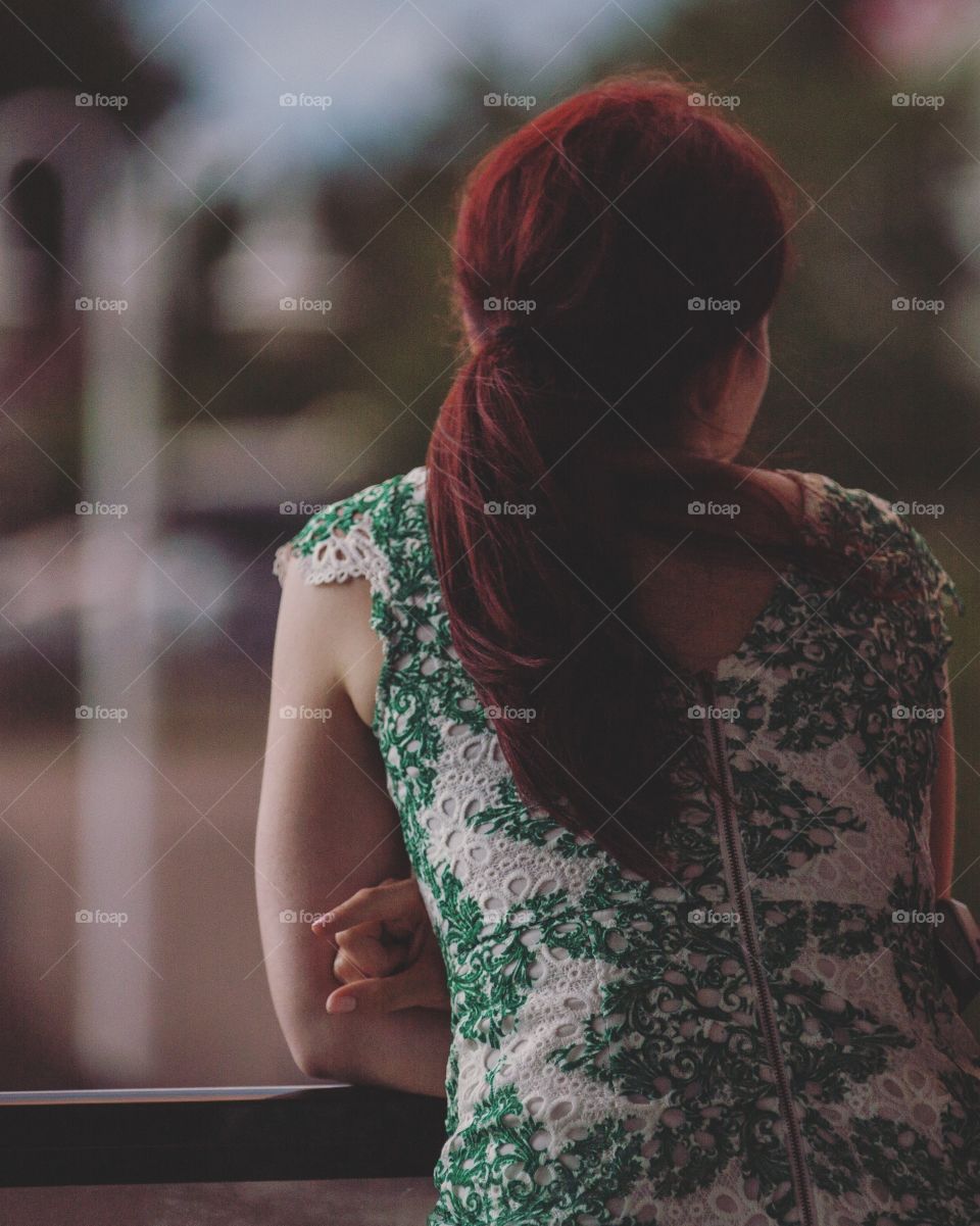 Girl with red hair in green dress overlooking a balcony
