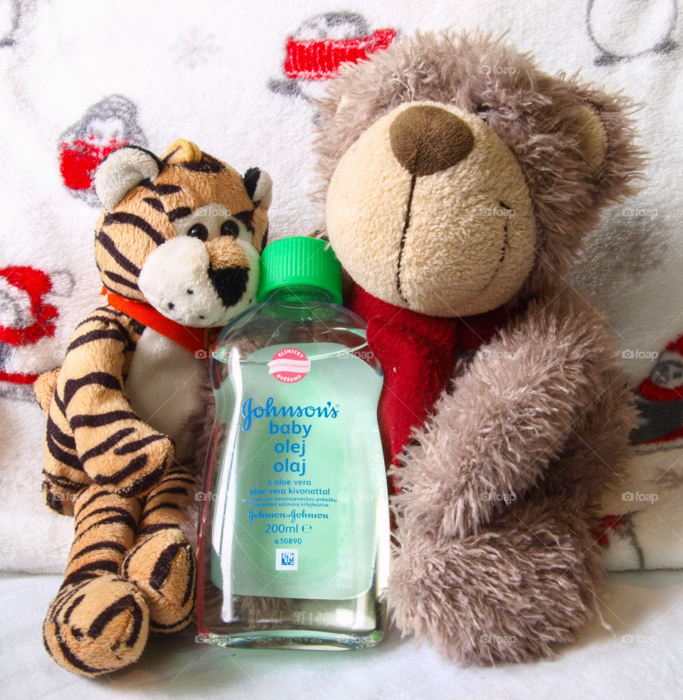 Plush toys on white sheet, Johnson's Baby oil in the middle.