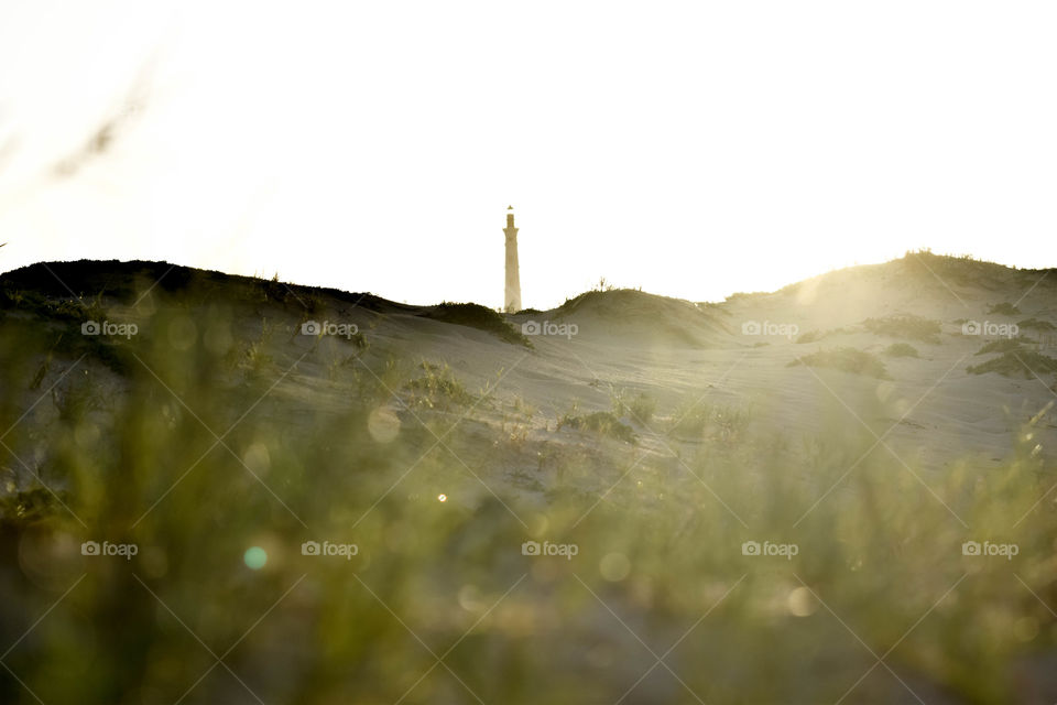 Lighthouse in distance on a beach with light bokeh