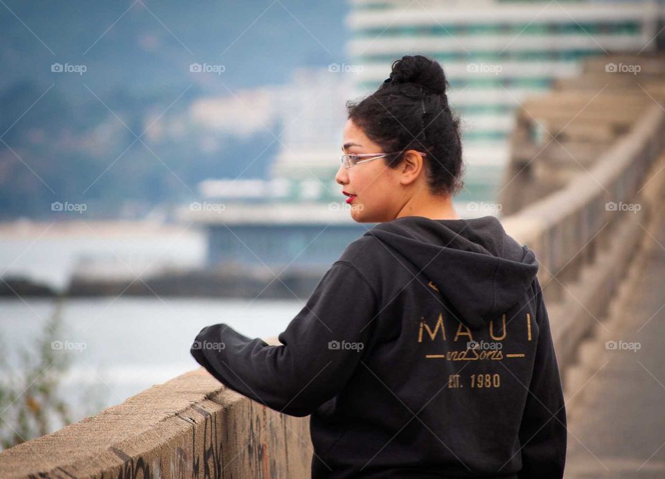 young woman with a black poleron taken hair, looking at the coast