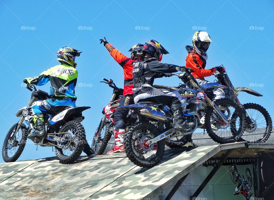 Motocross Stunt Team. Motorcycle Stunt Team Members Performing On A Ramp
