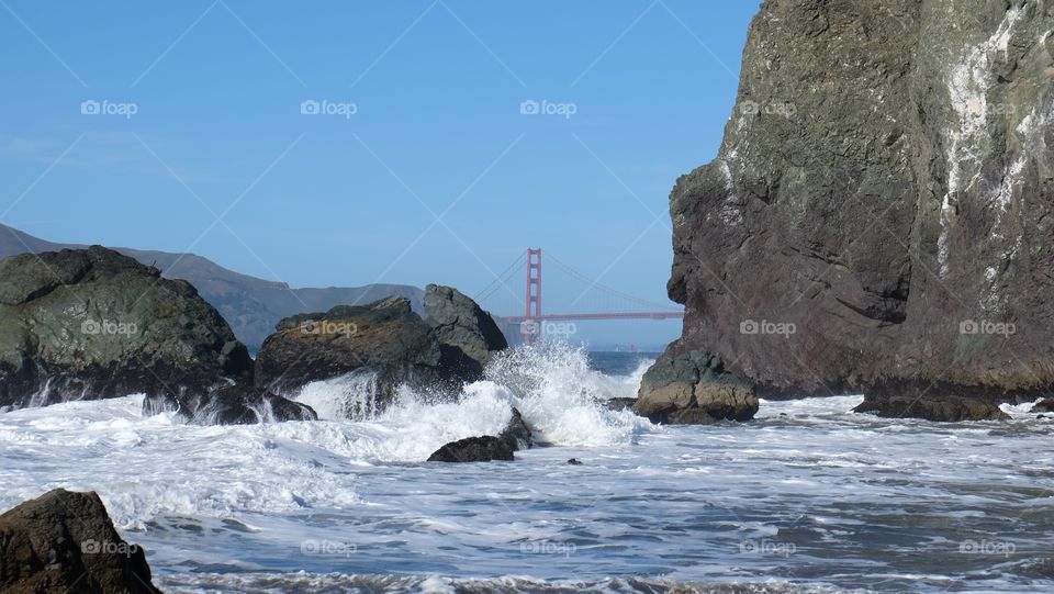 Mile rock beach SF. Playful waves crash and spray tiny delights of droplets on this beach. Golden Gate visible.