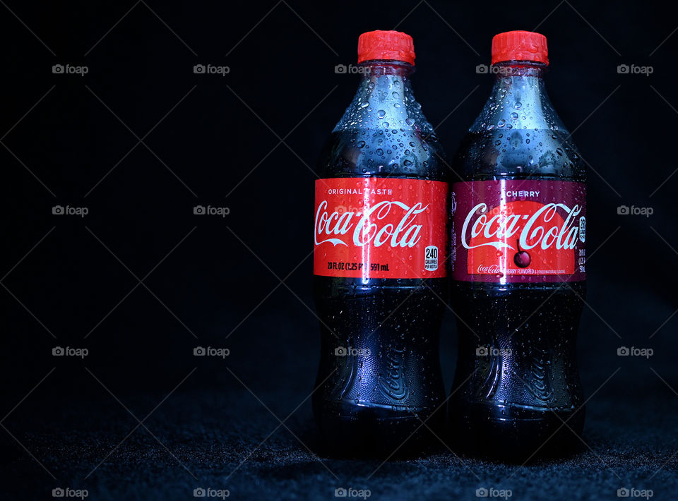 Close up shot of two Coca Cola with black background with the mists at the studio.  