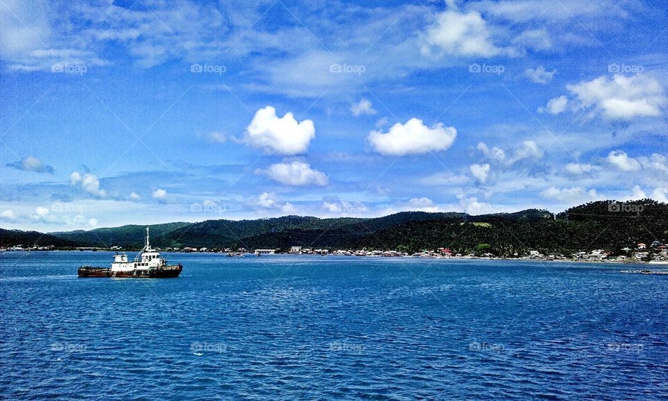 Natural landscape with thug boat navigating in a calm blue water.