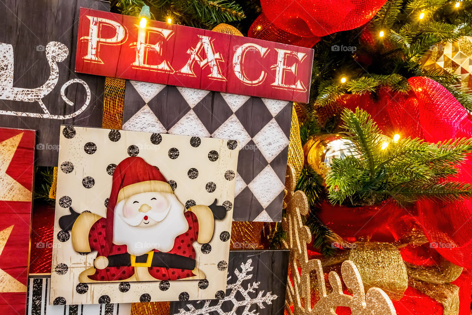Closeup view of a Christmas message on a tree that says "PEACE" artfully written on a board. The tungsten lighting gives the image a warm feeling.