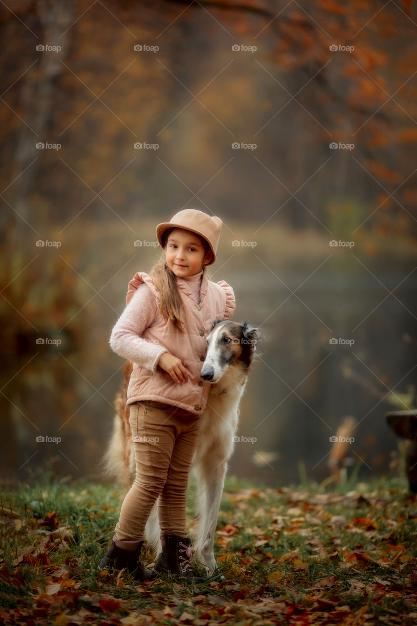 Cute smiling girl with borzoi dog in an autumn park 