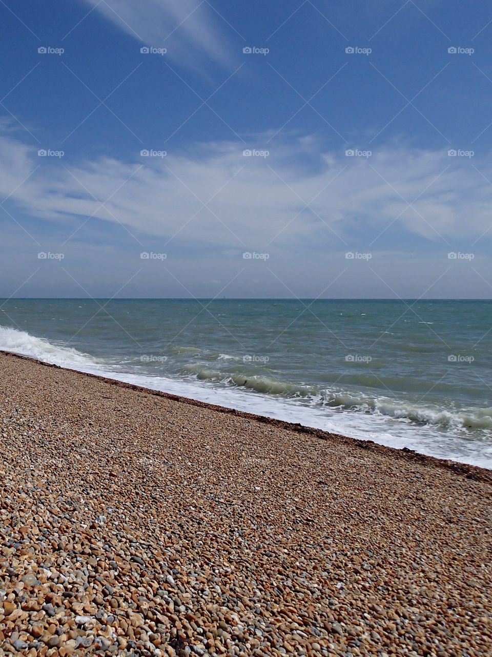 Rocky beach with waves near Folkestone in England on the Atlantic Ocean on a sunny summer day. 