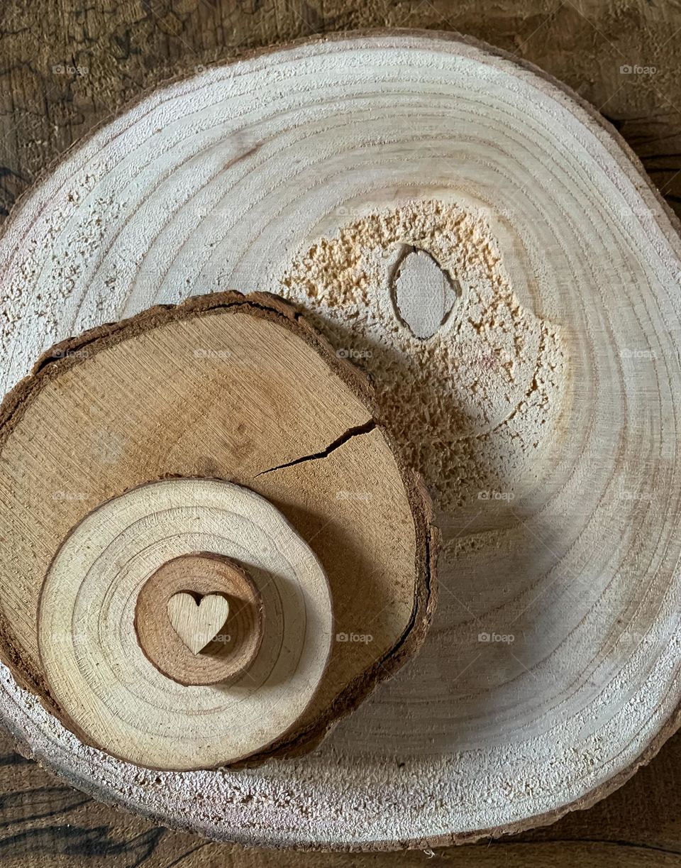 A tiny wooden heart on top of a stack of increasing in size wood cross sections 