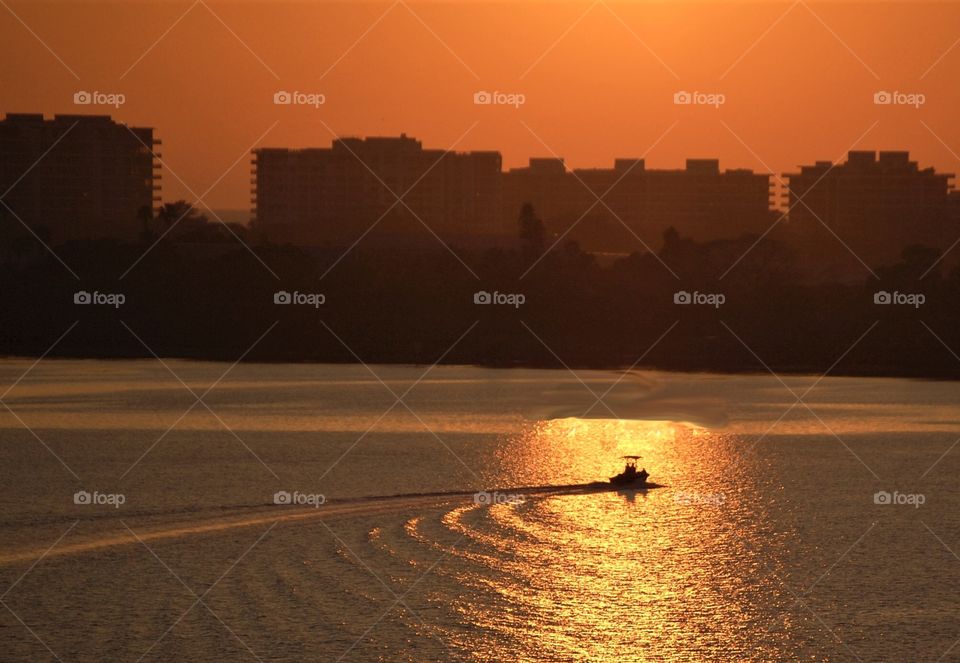 Summertime, beautiful sunset, boat on the ocean, city skyline