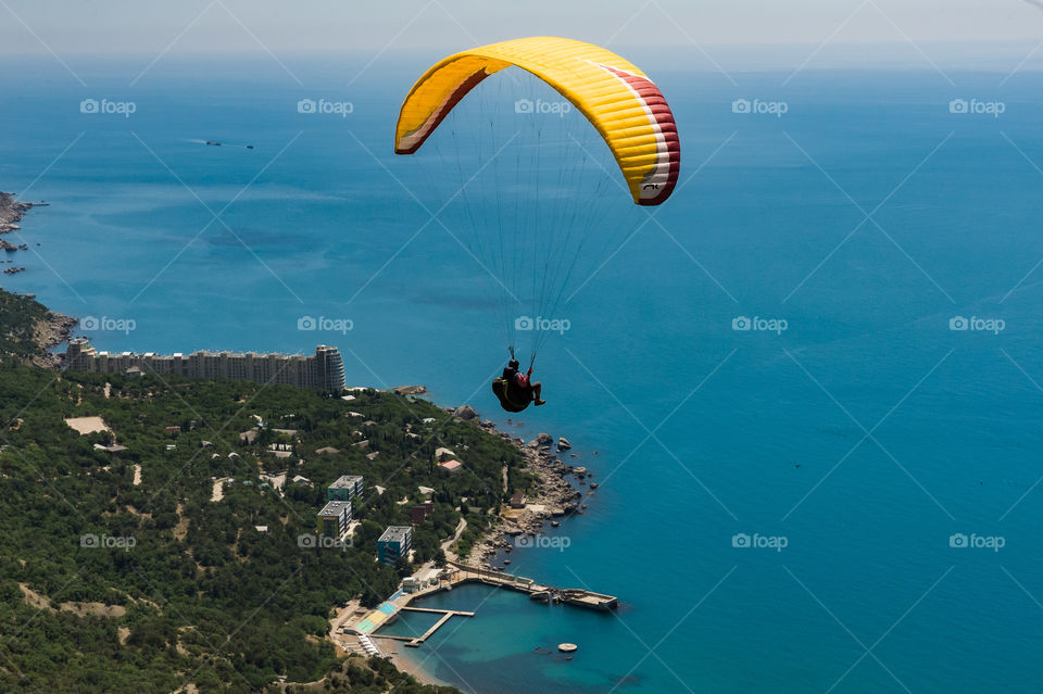 A man on a paraglider flies over the beautiful coast of the Black Sea