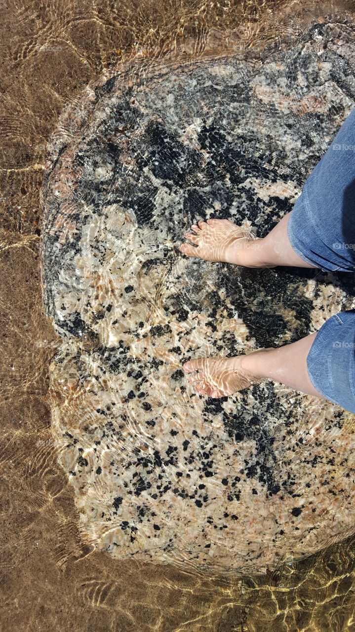 feet on a rock at the lake