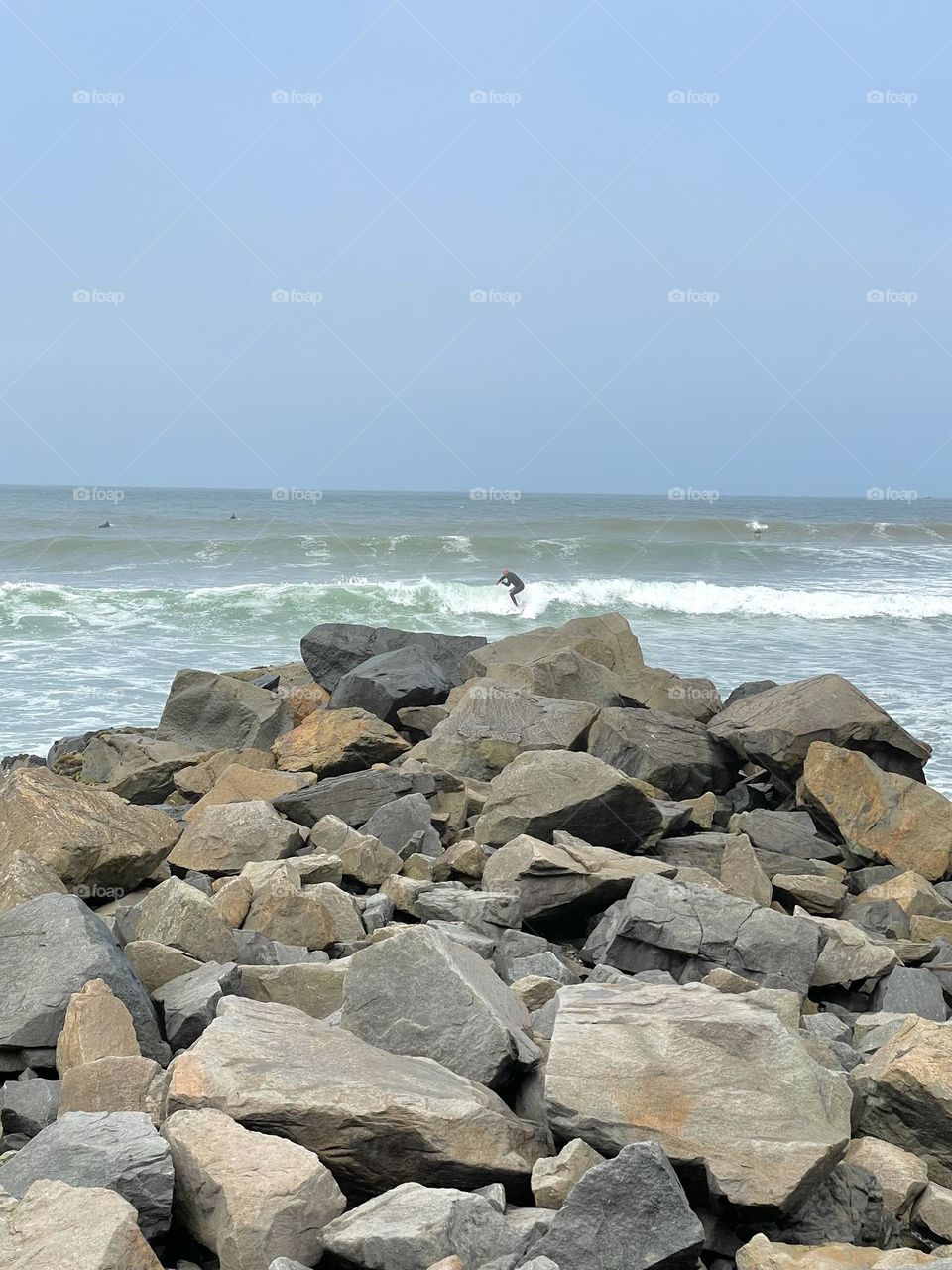Tiny surfer beyond the rocks