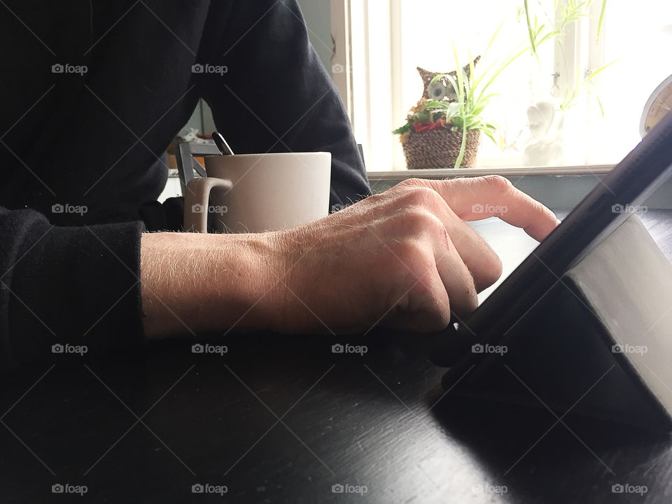 Man using a tablet while drinking coffee