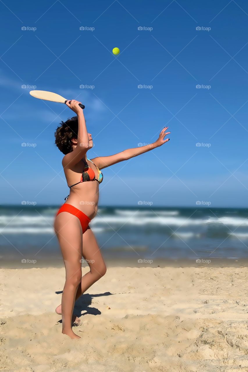 girl playing paddleball on the beach