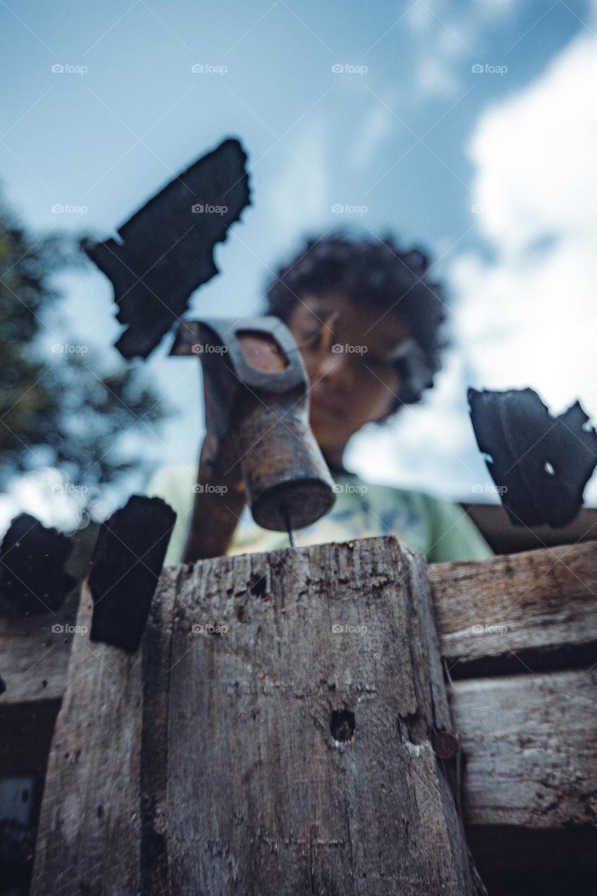 Person hammering a metal nail into wood