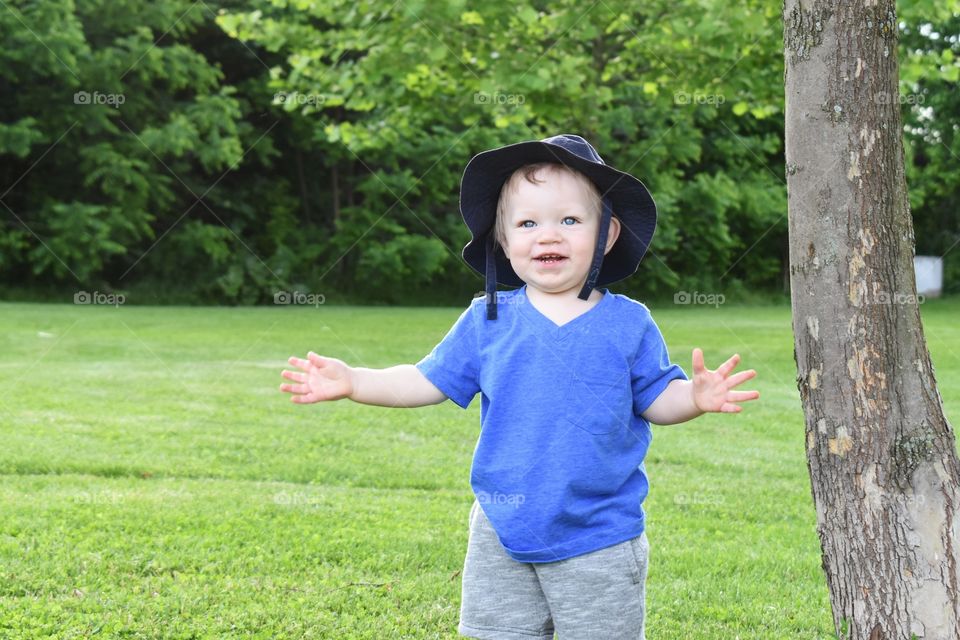 Cute toddler boy wearing hat having fun in nature park 