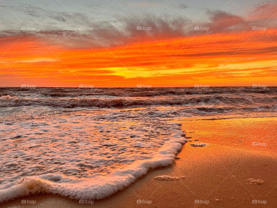A breathtaking and radiant sunset which colors the waves iridescent, often towers and collides the shore with great force. The impact of the waves against the coastline created a stunning display of energy and motion
