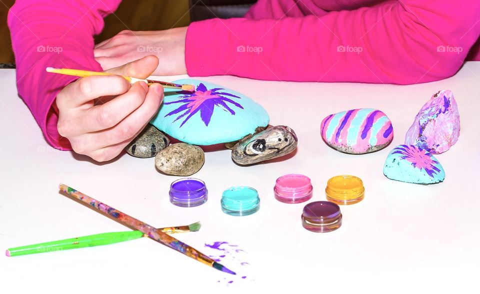 Child painting rocks and making a colourful and artistic turtle out of the stones 