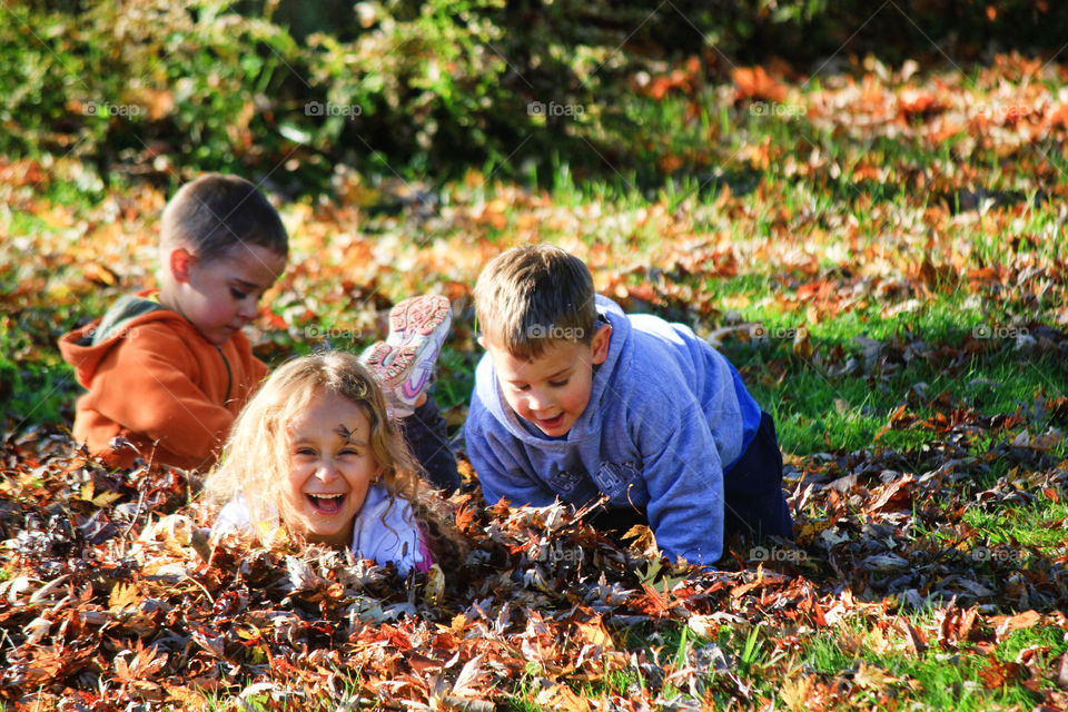Happy children playing on pile of dry leaves