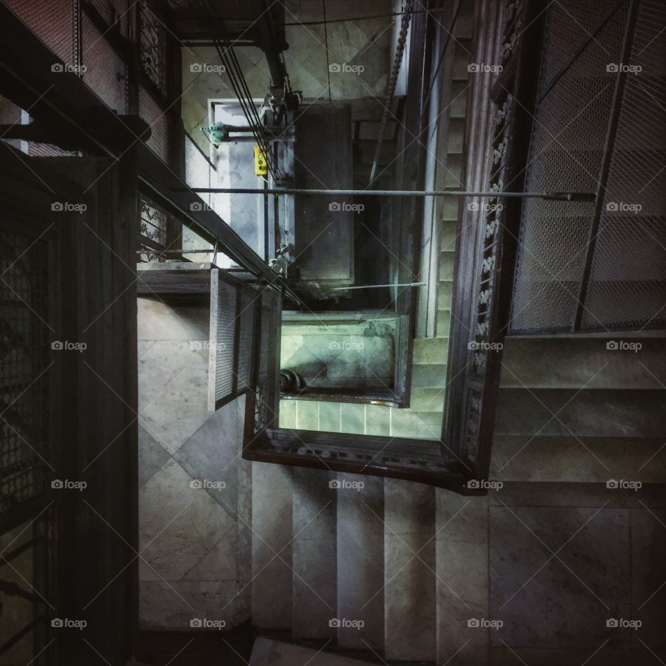 Elevator shaft next to a marble staircase in an old building in Salerno, Italy