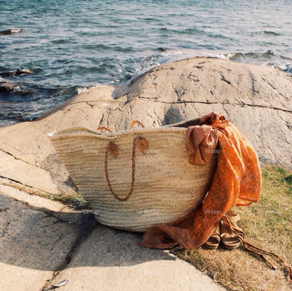 Straw bag,sandals and a silk dress on beach