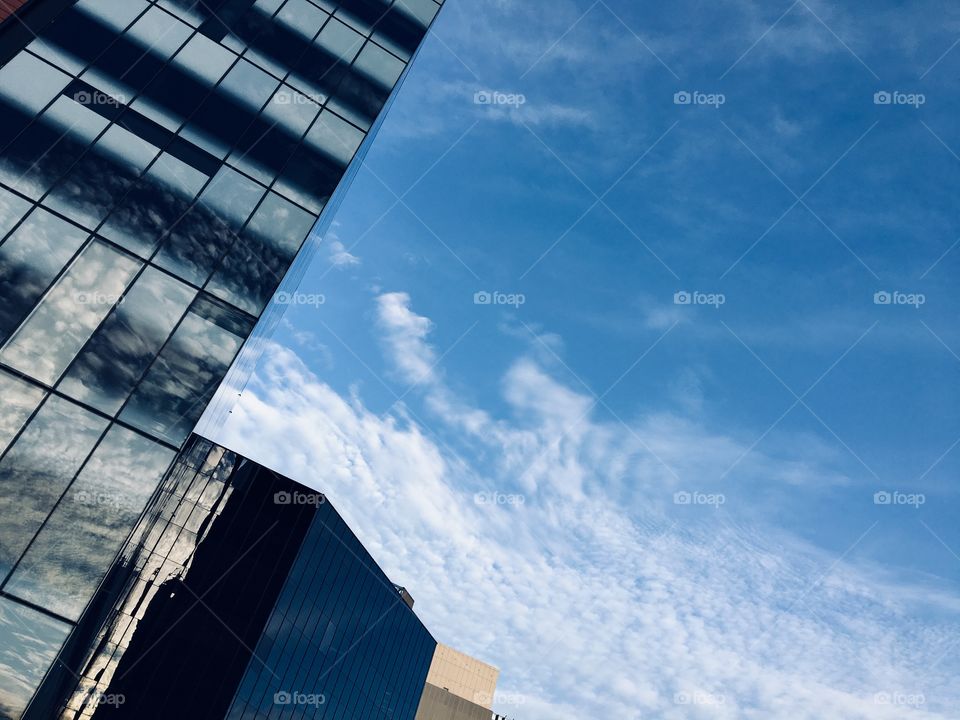 A cityscape: The pattern of clouds are reflected in the glasses of the building in urban area.