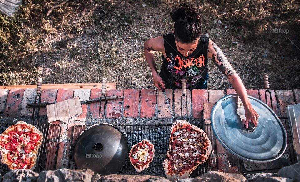 Pizza time. A women makes pizza in the outdoors on a bbq. 