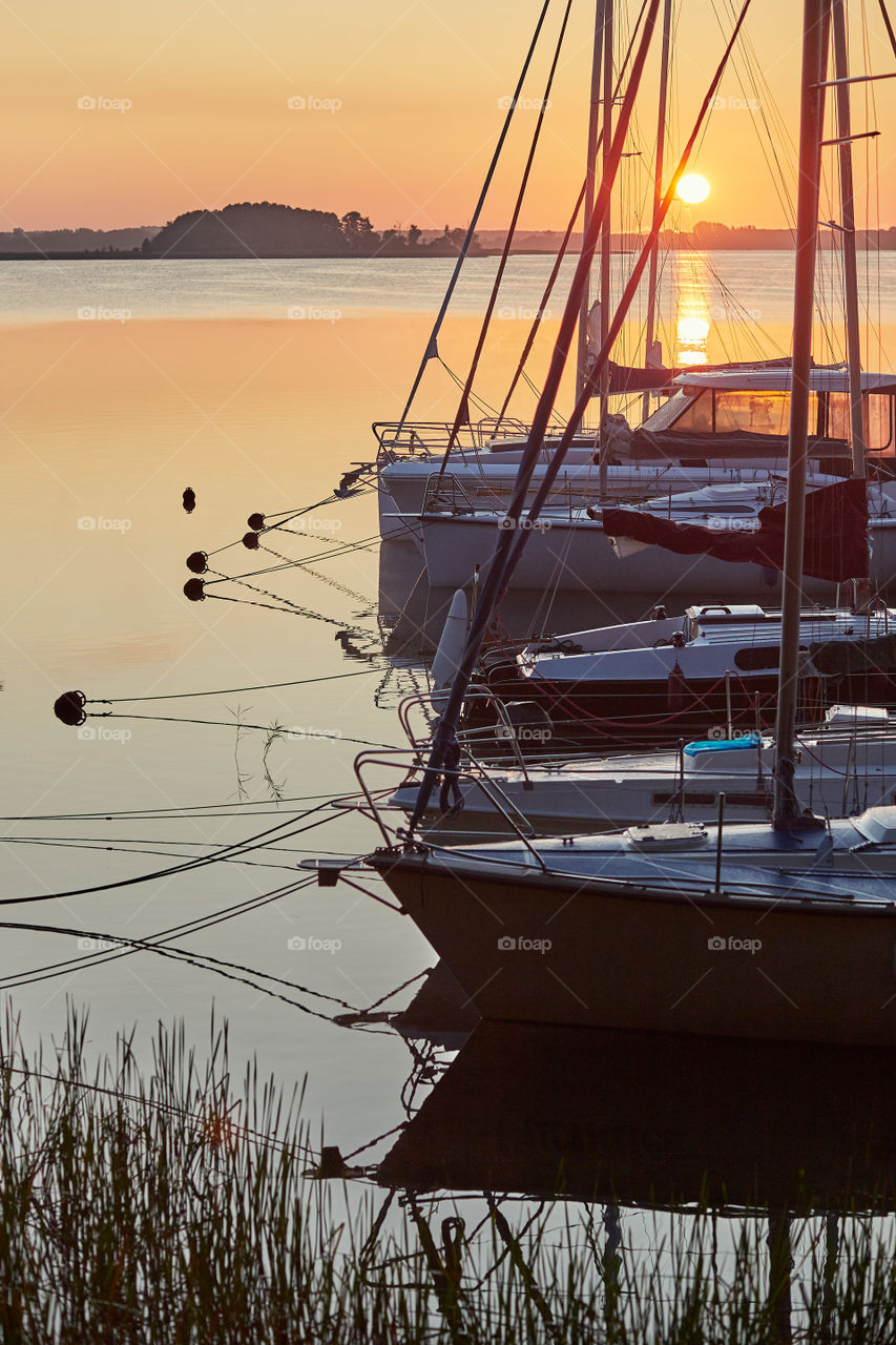 Yachts and boats moored in a harbour at sunrise. Candid people, real moments, authentic situations