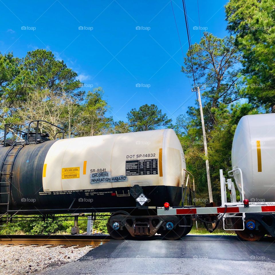 Tanker cars crossing over the road at intersection with blue sky
