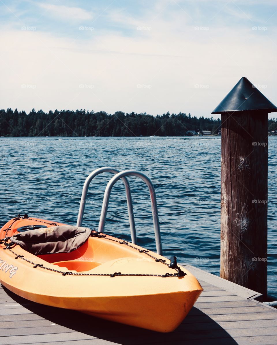 Keeping active by kayaking is a great opportunity to enjoy the outdoors while staying fit. A kayak sits on a  lakeside dock in the Pacific Northwest.