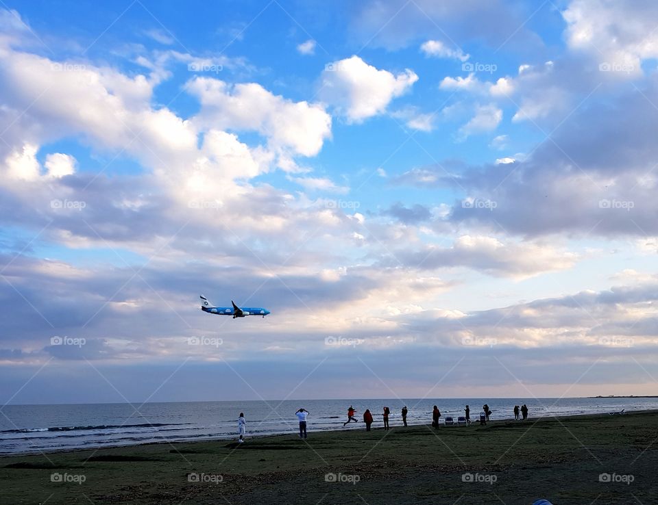 People on a beautiful and quiet beach at sunset, admiring the landing of aeroplanes at a near-by airport.