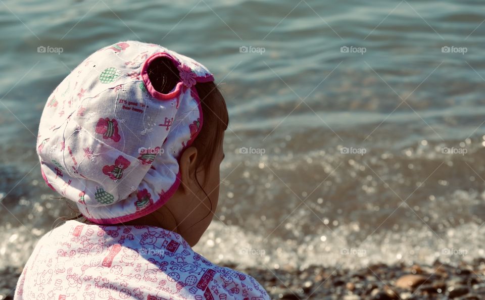 little girl in sun panama looks thoughtfully at the sea