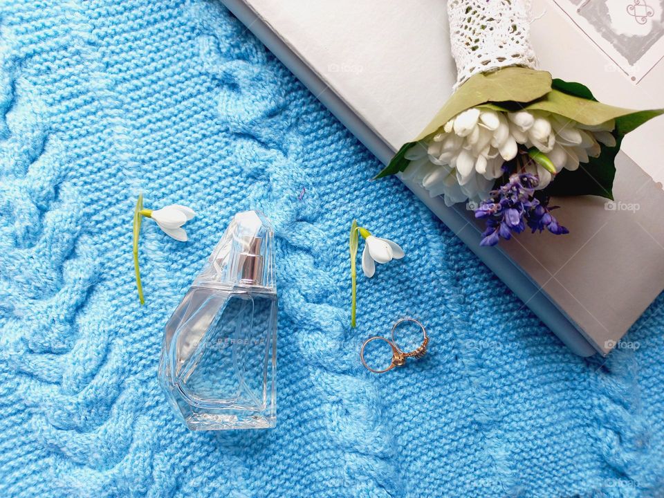 perfume and snowdrops on a blue sweater.