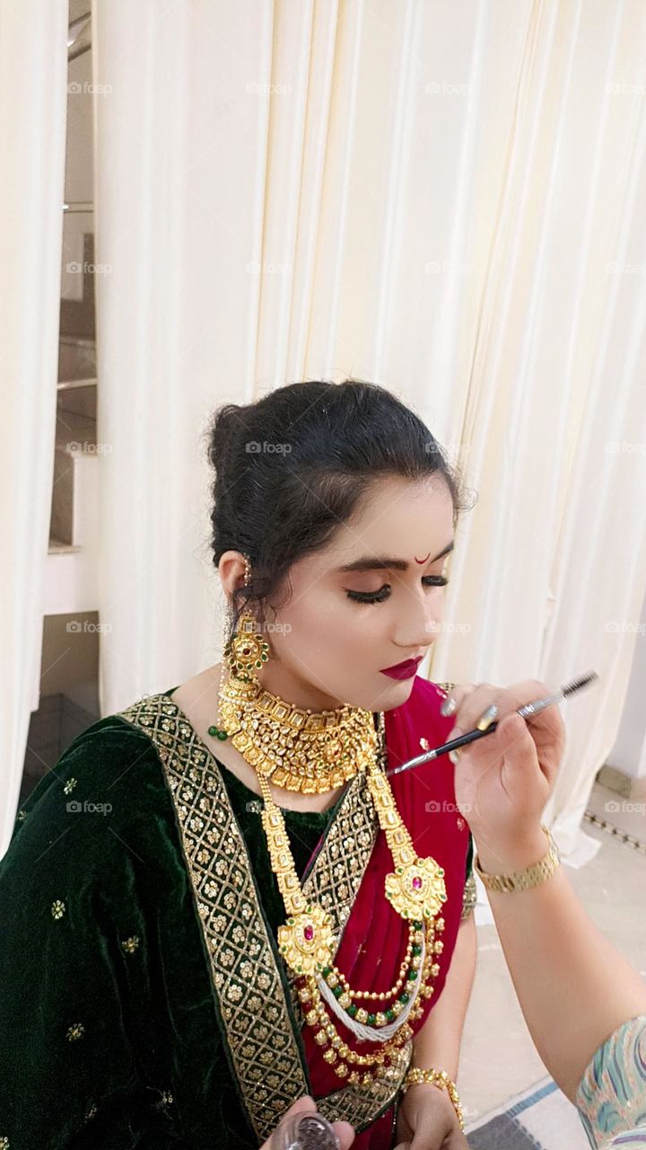 potrate of a beautiful young girl with red and green marathi getup with background cream in color.