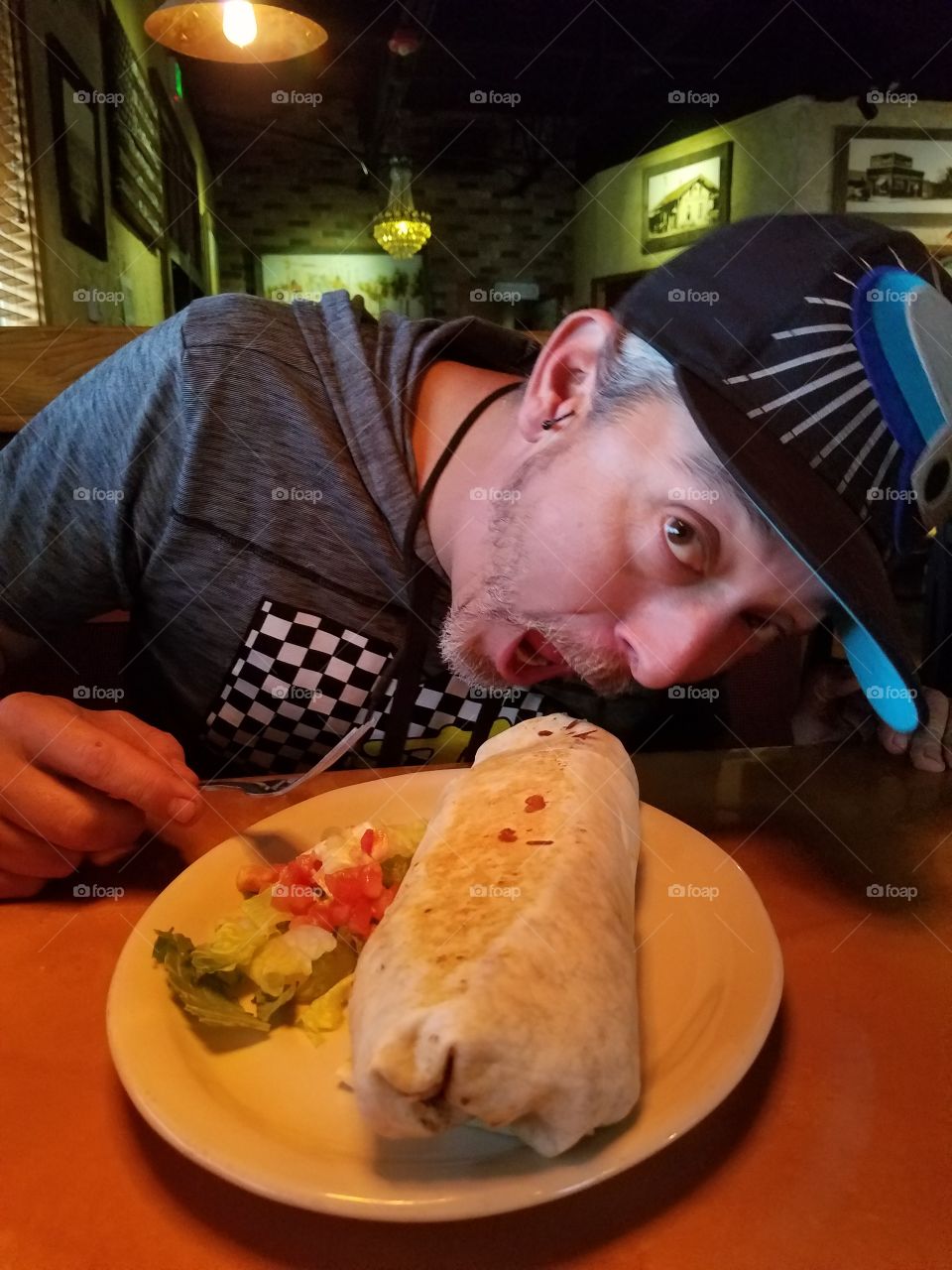 Eating a giant Colorado style burrito that is way too big for his mouth at a local Mexican restaurant.