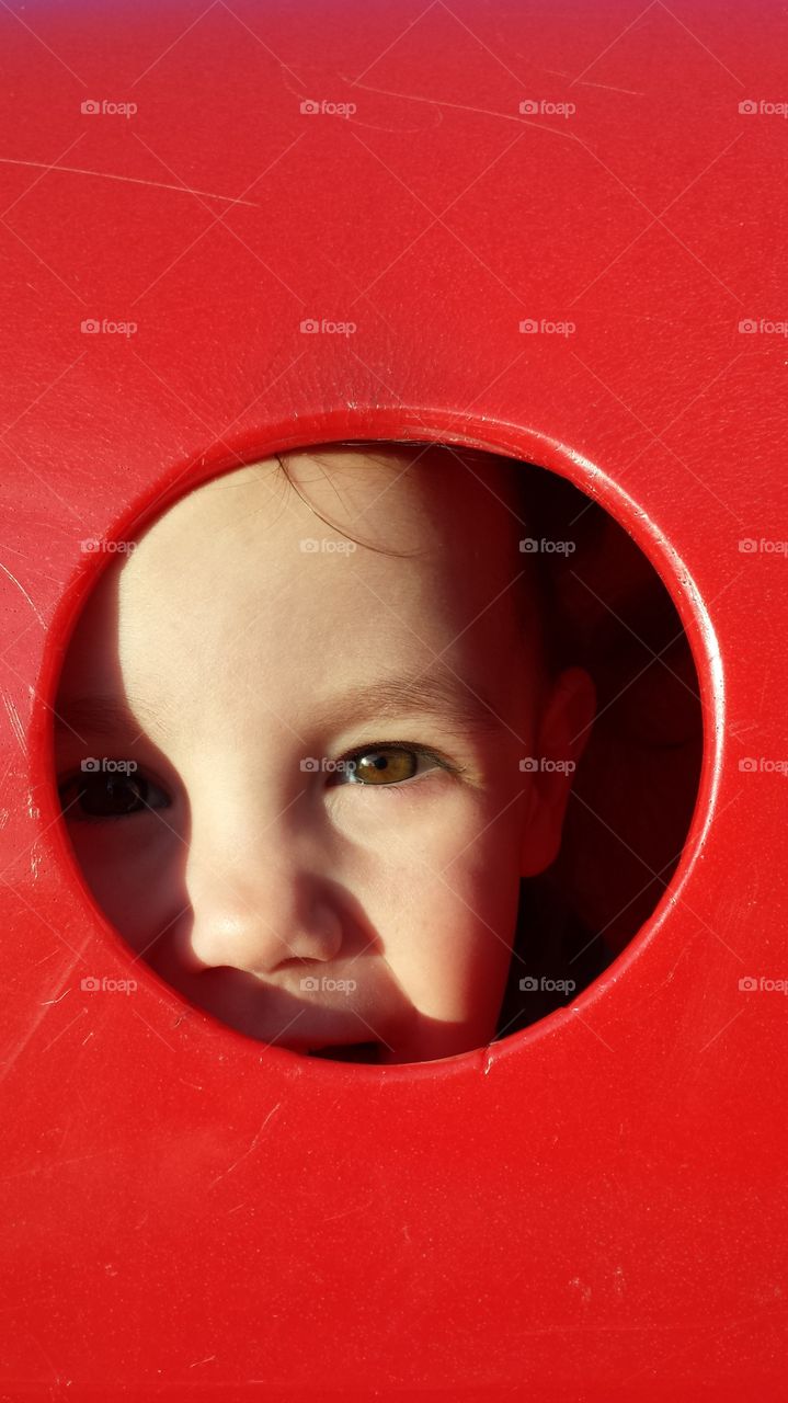 Red and Eye. my daughter peeking out a portal on the playground