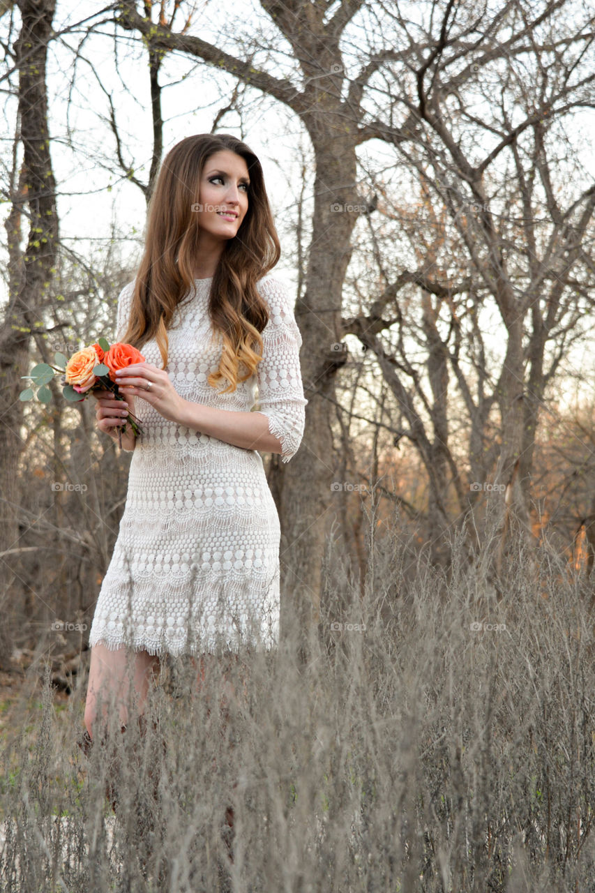 Gorgeous girl holding rose flowers near bare trees