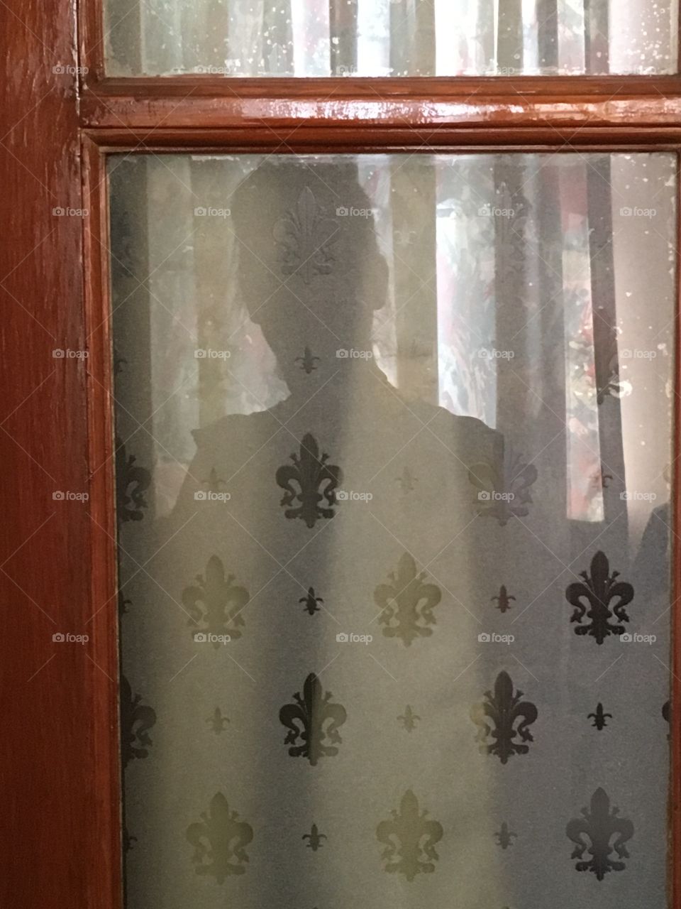 Reflection of woman captured in glass window pane of door